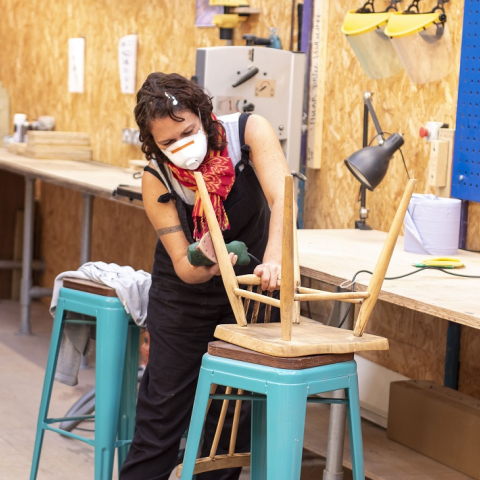 Image of a person sanding chair legs inside woodwork studio
