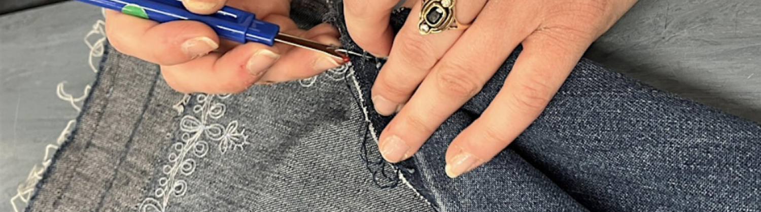 Pair of hands sewing at an upcycling workshop