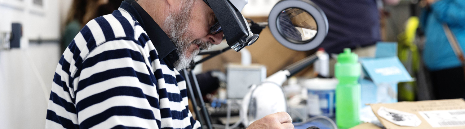 Man with magnifying glasses fixing an electrical item