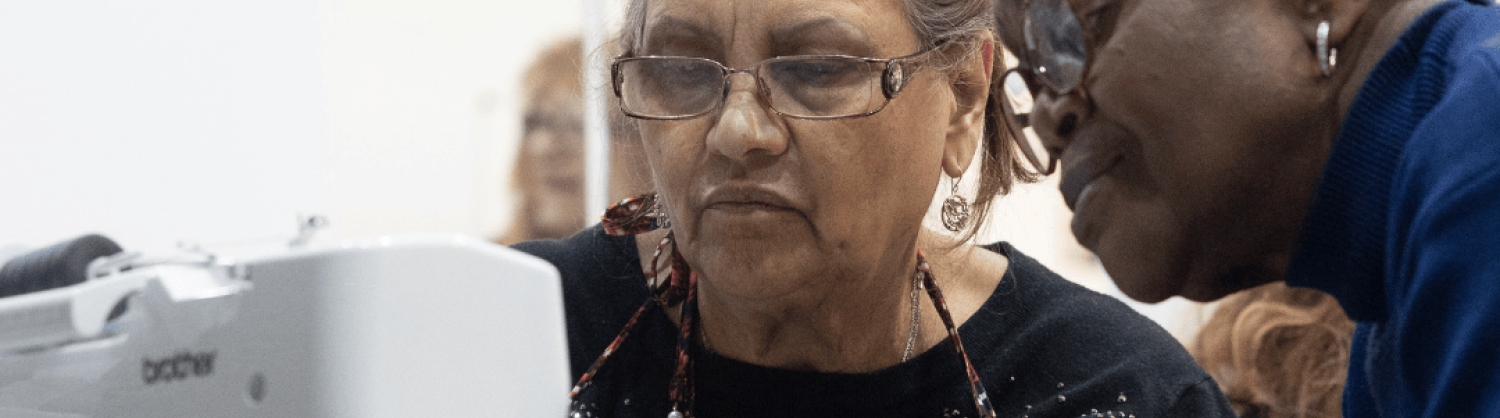 Two women working at a sewing machine at an Arachne workshop