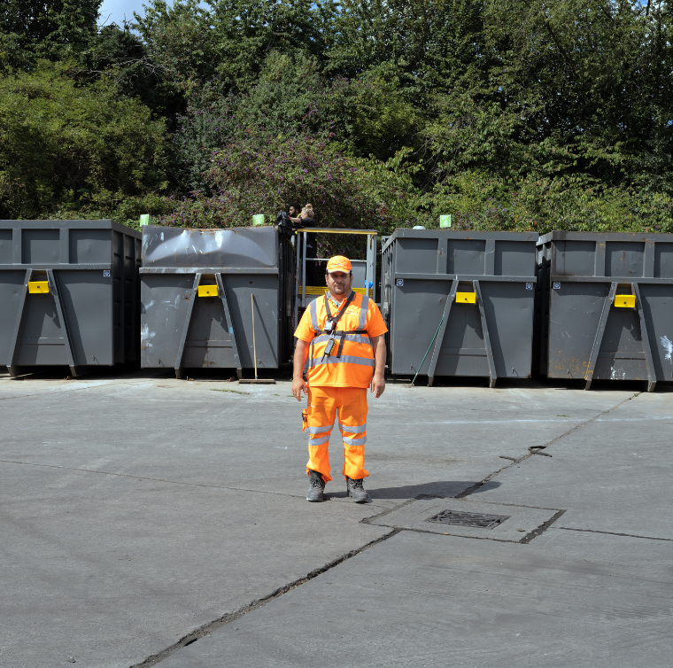 A staff member stands in front of the bunkers at the recycling centre