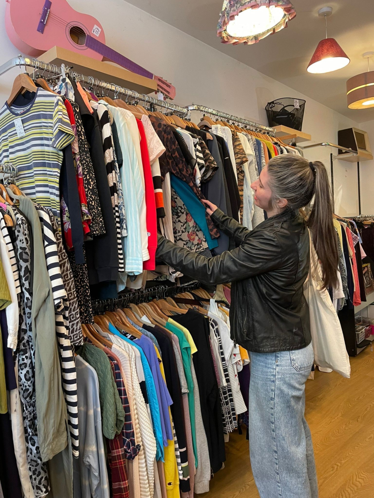 Woman looking through clothes rails in a charity shop
